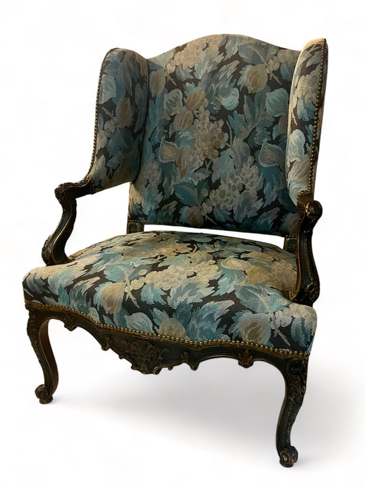 A antique 19th century French parcel gilt winged back arm chair, supported by 4 carved
